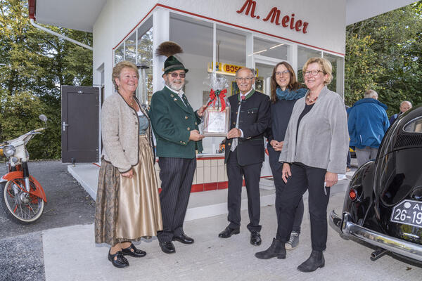 Familie Meier übergibt einen original Gasolin-Schlüsselanhänger an Bezirkstagspräsident Josef Mederer.