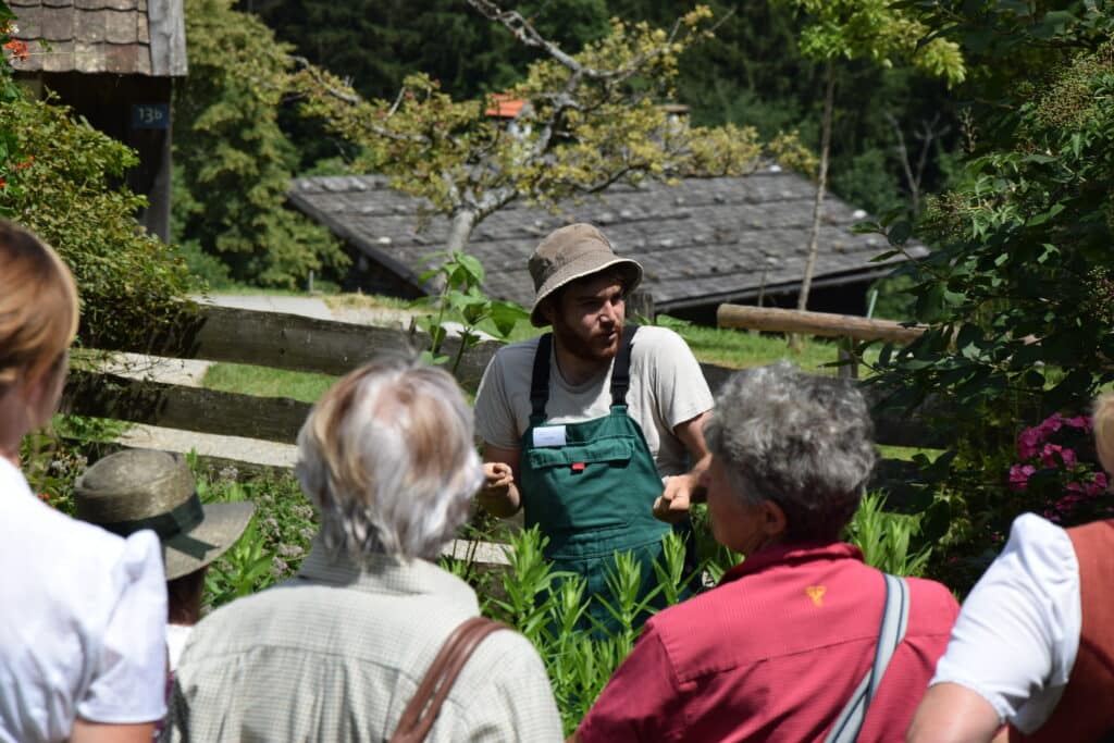 Mehrere Menschen schauen zu einem Mann im Garten.