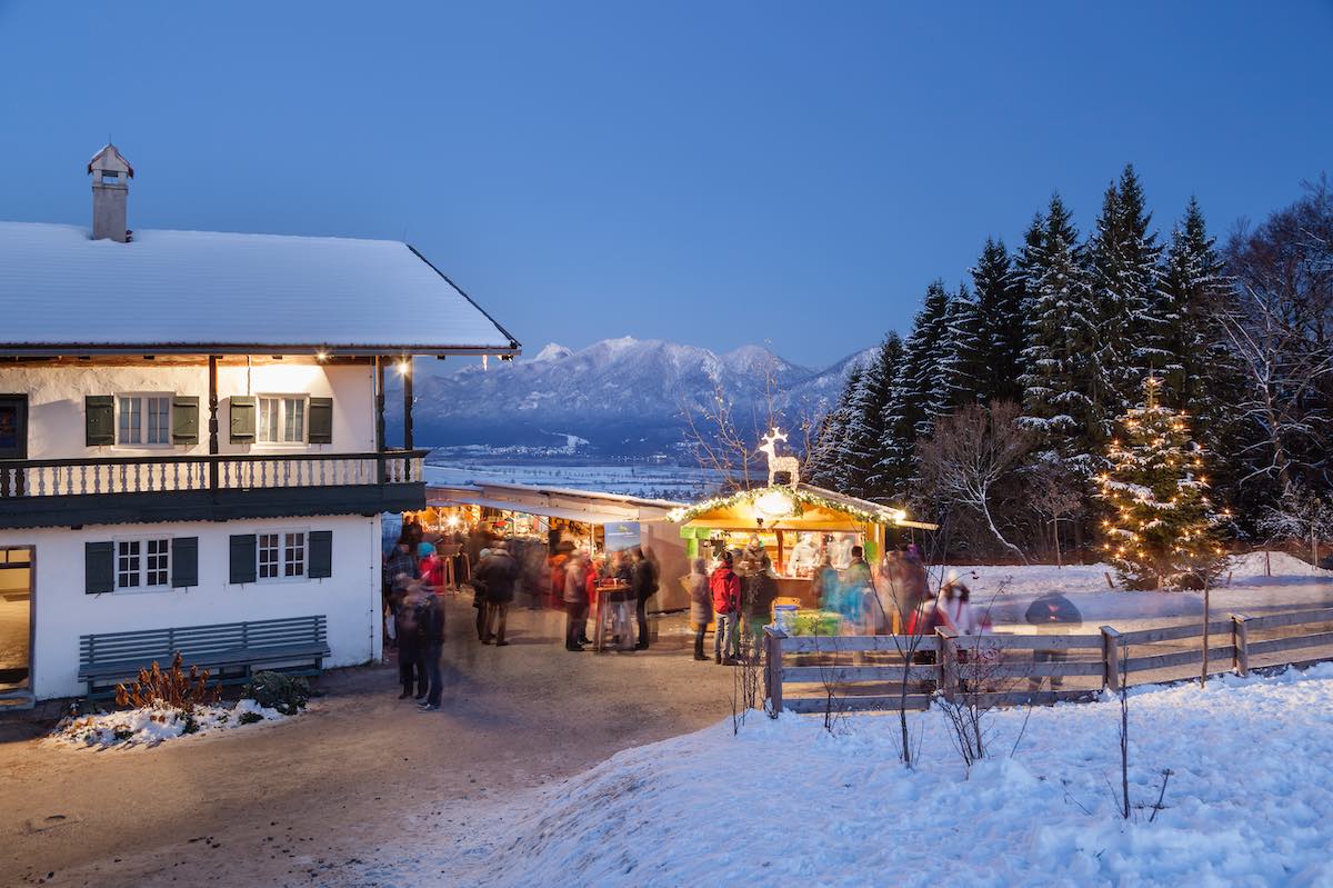 Weihnachtsmarktbuden am Abend vor Bergkulisse