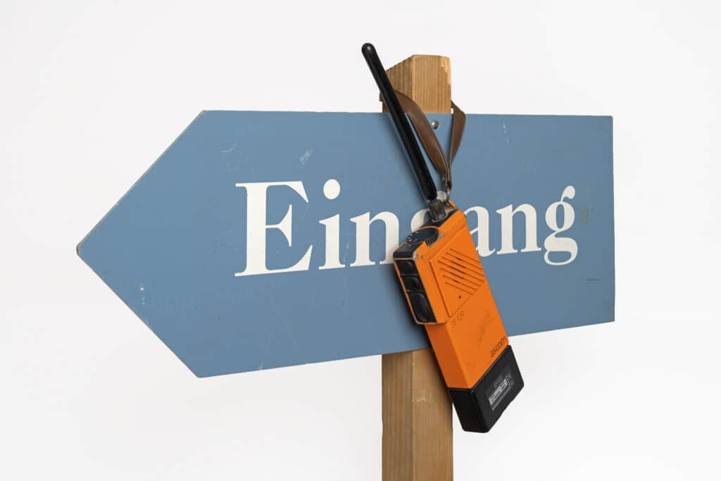 Altes, orangefarbenes Funkgerät, das über einem Schild hängt, auf dem "Eingang" steht.