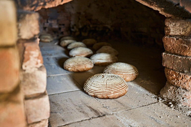 Mehrere Brotlaibe befinden sich in einem alten Backofen.