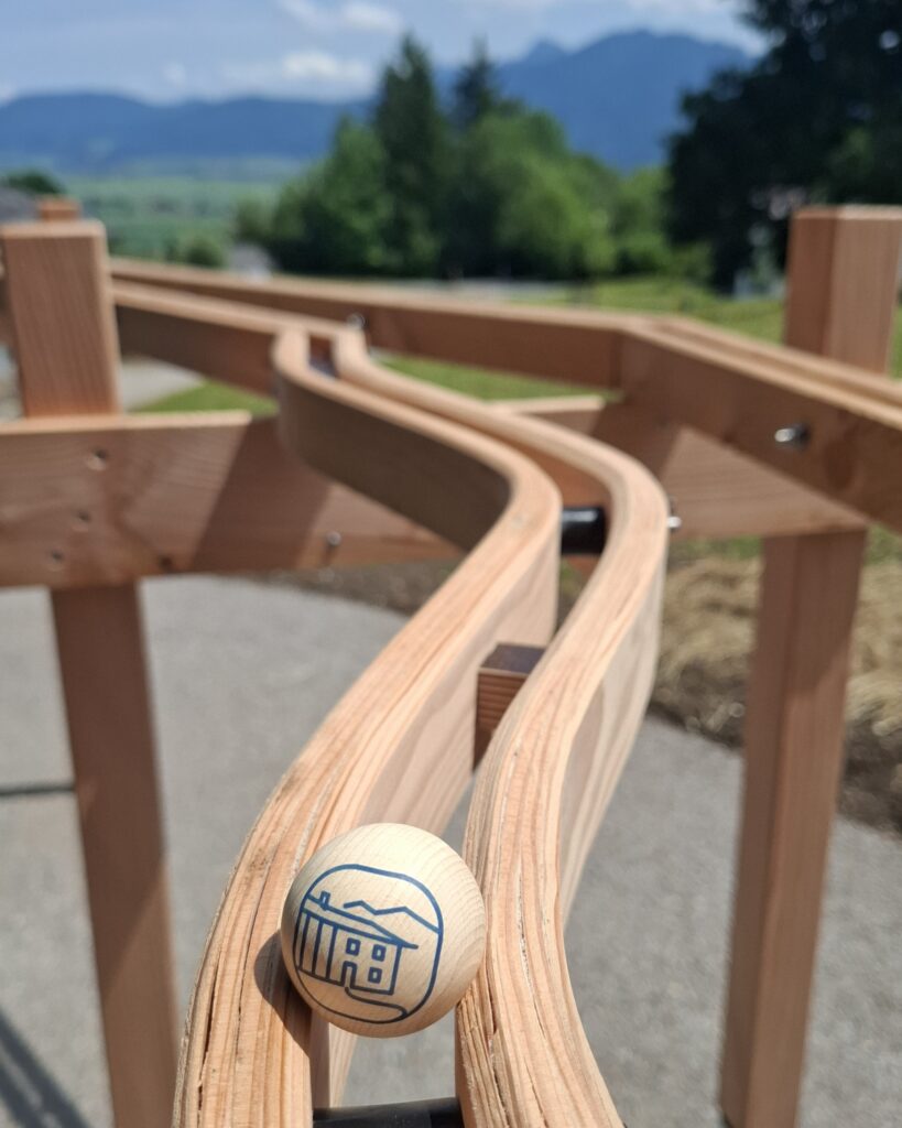 Eine Holzkugel rollt über eine Kugelbahn.